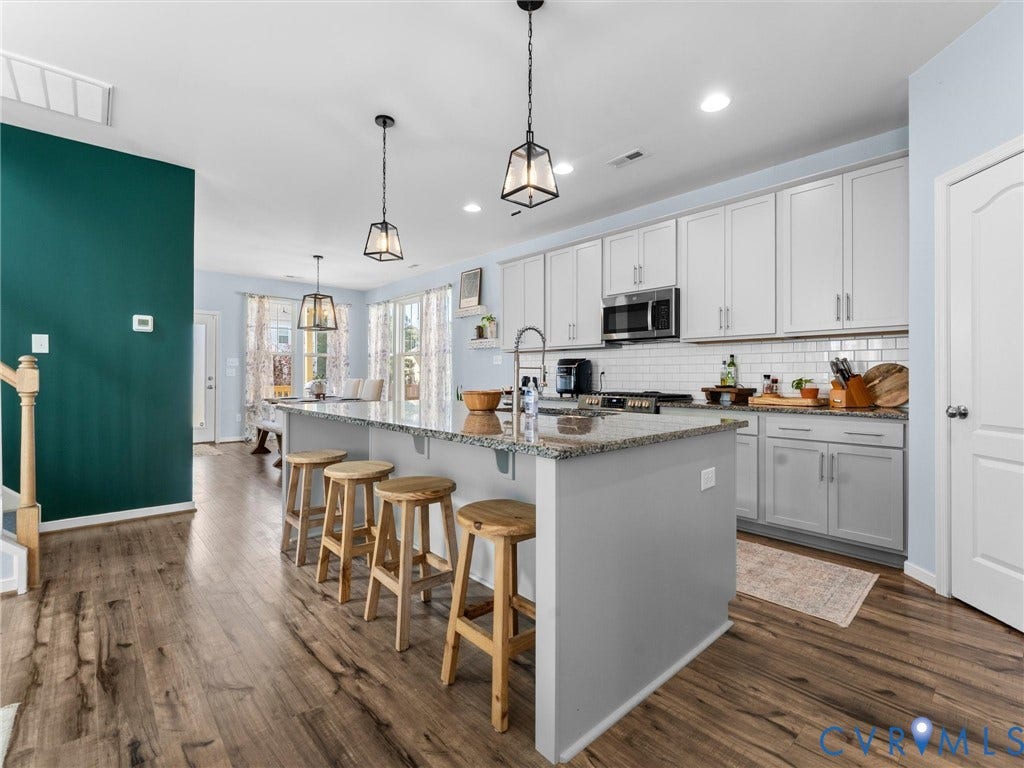 5726 Gossamer Place, Wynwood At FoxCreek, Moseley, VA 23120 Kitchen featuring wood-finish flooring, a stone-topped island, white shaker-style cabinetry, a white subway tile backsplash, and decorative pendant lighting