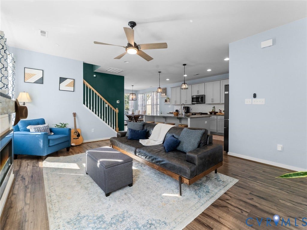5726 Gossamer Place, Wynwood At FoxCreek, Moseley, VA 23120 Open-concept interior featuring wood-finish flooring, a kitchen island, pendant lighting, a ceiling fan, and a staircase with a wooden handrail