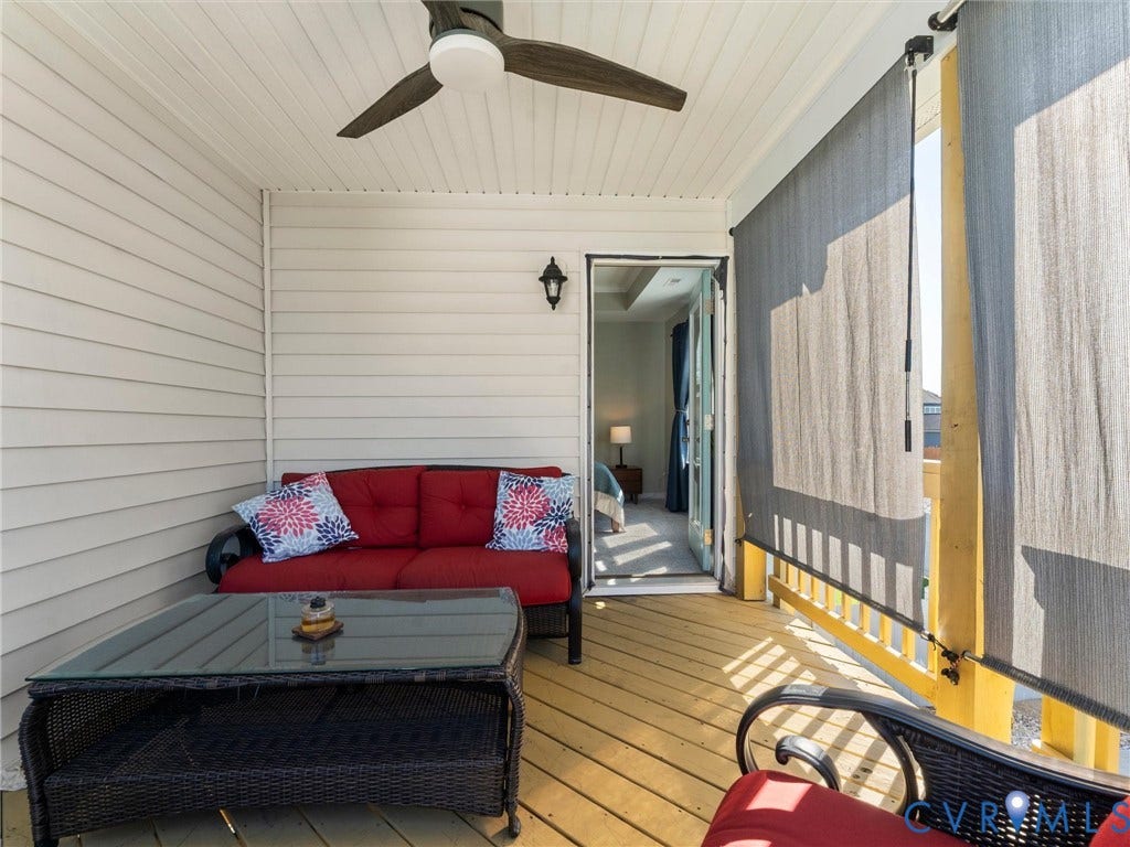 5726 Gossamer Place, Wynwood At FoxCreek, Moseley, VA 23120 Covered balcony featuring horizontal lap siding, beadboard ceiling, ceiling fan with integrated lighting, wall-mounted lantern-style sconce, and wood-finish decking
