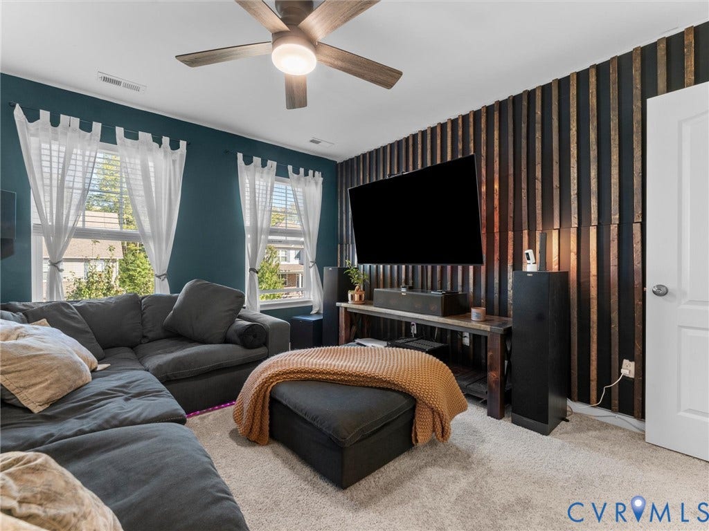 5726 Gossamer Place, Wynwood At FoxCreek, Moseley, VA 23120 Room featuring a vertical wood-slat accent wall, dual windows, and a ceiling fan with integrated lighting