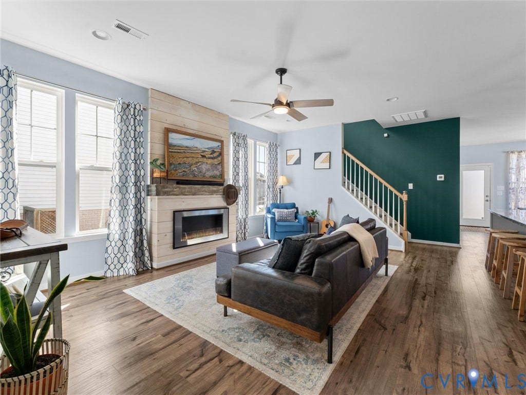 5726 Gossamer Place, Wynwood At FoxCreek, Moseley, VA 23120 Wood-finish flooring, fireplace with horizontal wood-plank accent wall, ceiling fan, and staircase with wooden handrail