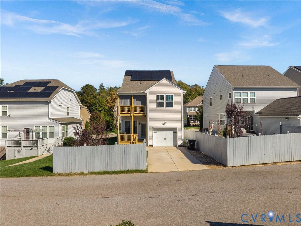5726 Gossamer Place, Wynwood At FoxCreek, Moseley, VA 23120 Two-story residence featuring light-colored horizontal siding, rooftop solar panels, a single-car garage, and a multi-level wood-railed deck