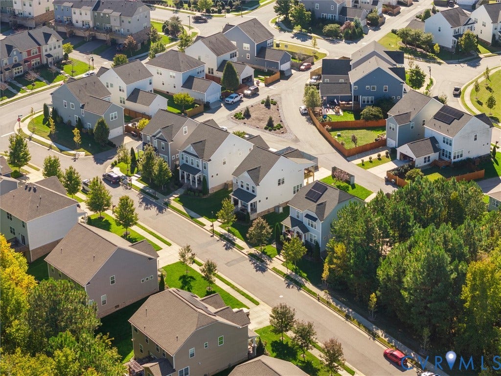 5726 Gossamer Place, Wynwood At FoxCreek, Moseley, VA 23120 Aerial perspective of a suburban neighborhood featuring paved streets, established landscaping with mature trees, and residential properties with varied rooflines and solar panel installations