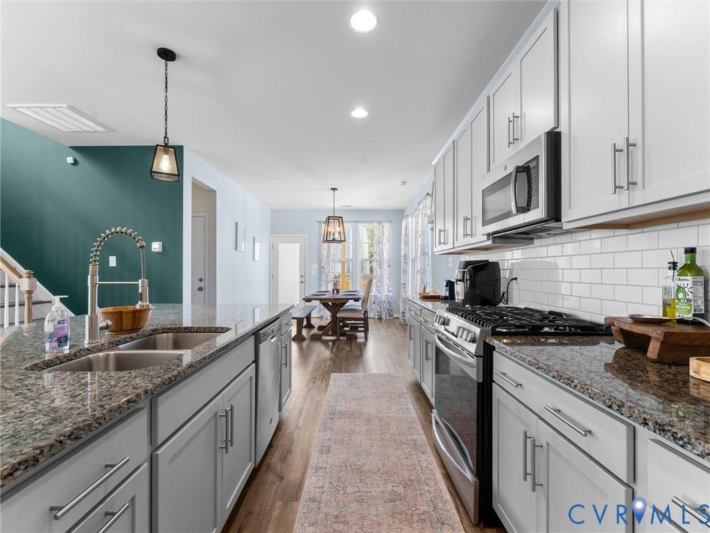 5726 Gossamer Place, Wynwood At FoxCreek, Moseley, VA 23120 Kitchen featuring stone countertops, white shaker-style cabinetry, subway tile backsplash, stainless steel gas range, and a large center island with an undermount sink