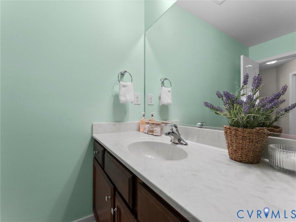 5726 Gossamer Place, Wynwood At FoxCreek, Moseley, VA 23120 Vanity featuring dark wood cabinetry, an integrated stone-composite countertop with an oval under-mount sink, polished chrome faucet, and a large wall-mounted mirror