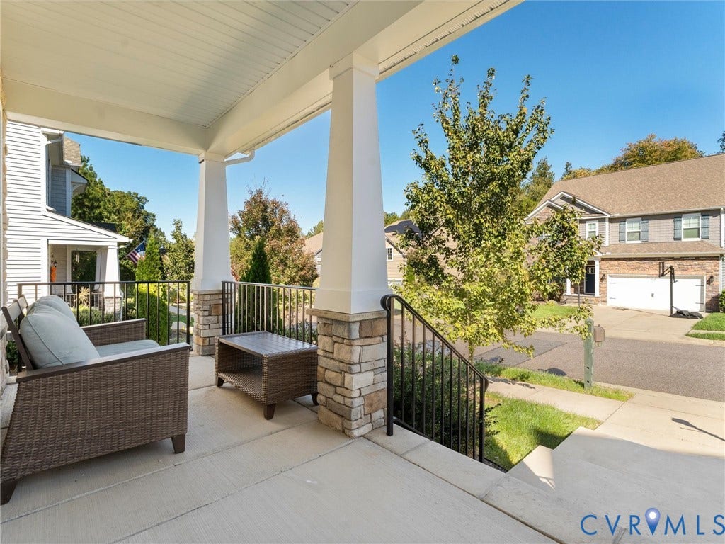 5726 Gossamer Place, Wynwood At FoxCreek, Moseley, VA 23120 Covered front porch featuring concrete flooring, tapered columns with stone-veneer bases, and black metal railings