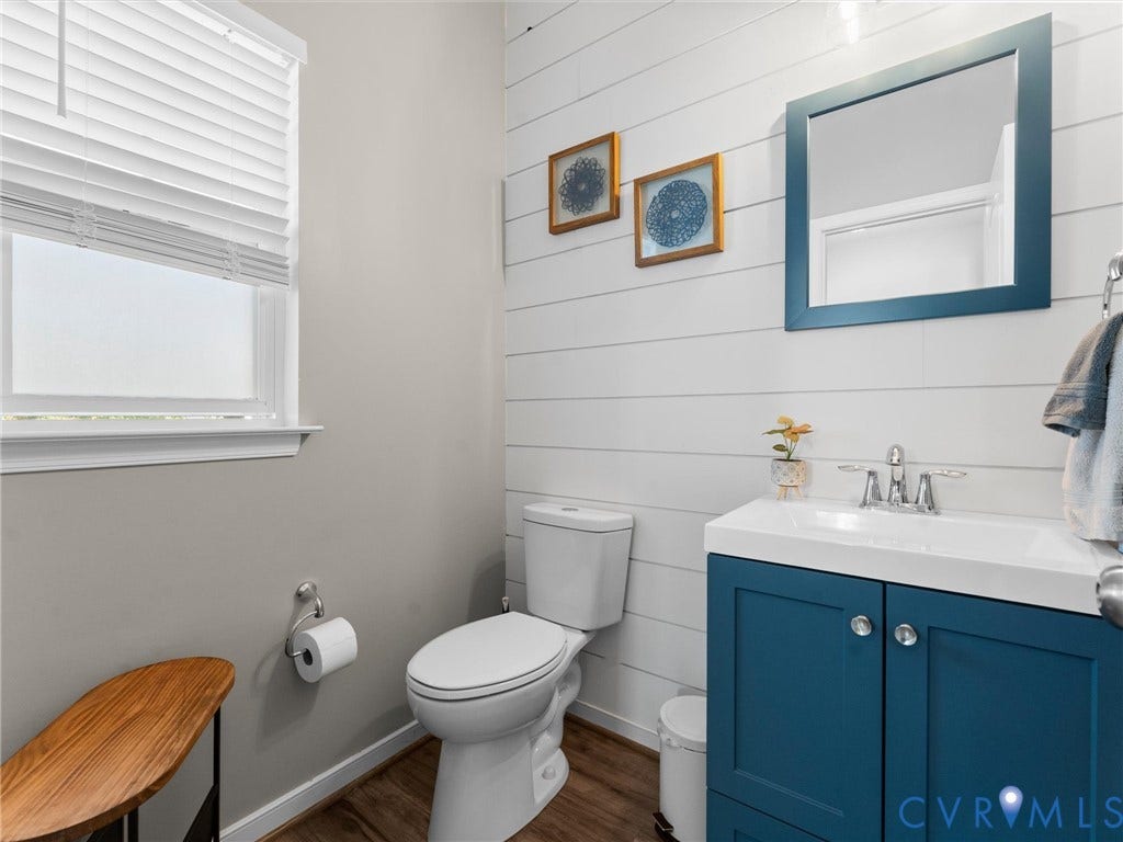 5726 Gossamer Place, Wynwood At FoxCreek, Moseley, VA 23120 Horizontal plank wall paneling, deep-toned blue vanity cabinet with a crisp white basin, polished chrome faucet, and wood-finish flooring