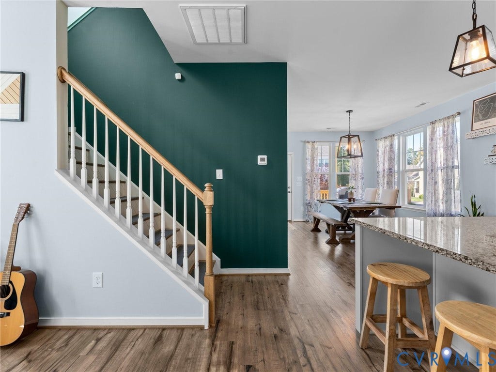 5726 Gossamer Place, Wynwood At FoxCreek, Moseley, VA 23120 Staircase with wooden handrail and white balusters, wood-finish flooring, accent wall, and stone-surface kitchen island