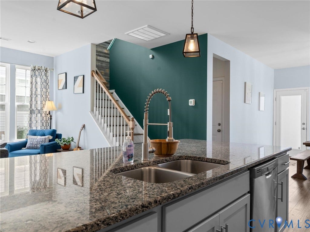 5726 Gossamer Place, Wynwood At FoxCreek, Moseley, VA 23120 Kitchen island with stone-surface countertop, stainless steel dual-basin undermount sink, gooseneck faucet, gray cabinetry, and wooden staircase with white balusters