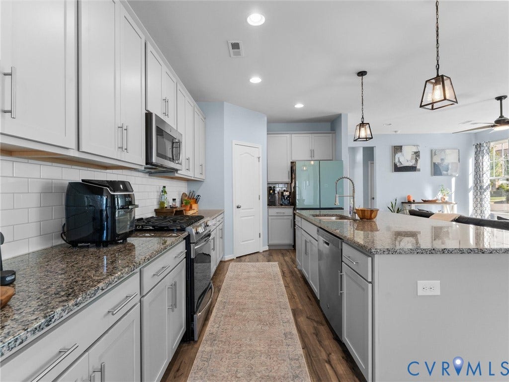 5726 Gossamer Place, Wynwood At FoxCreek, Moseley, VA 23120 Kitchen featuring shaker-style cabinetry, stone countertops, a subway tile backsplash, stainless steel appliances, and wood-finish flooring
