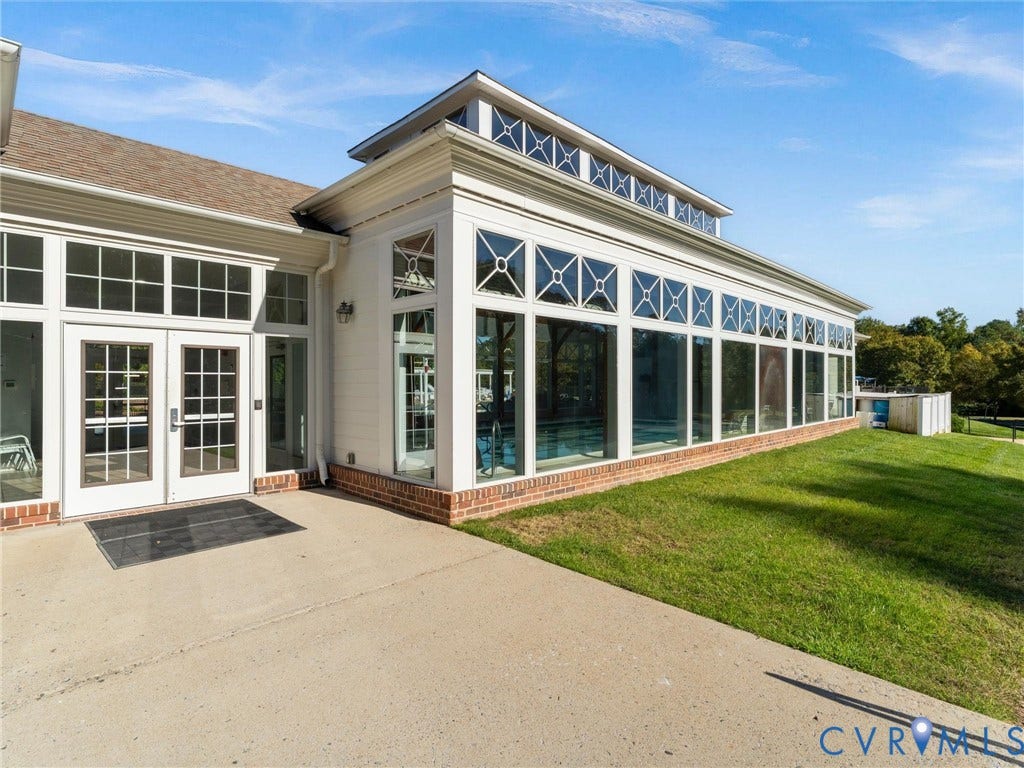 5726 Gossamer Place, Wynwood At FoxCreek, Moseley, VA 23120 Exterior featuring expansive glass wall panels with grid detailing, clerestory windows, brick foundation base, double-door entryway, and concrete patio