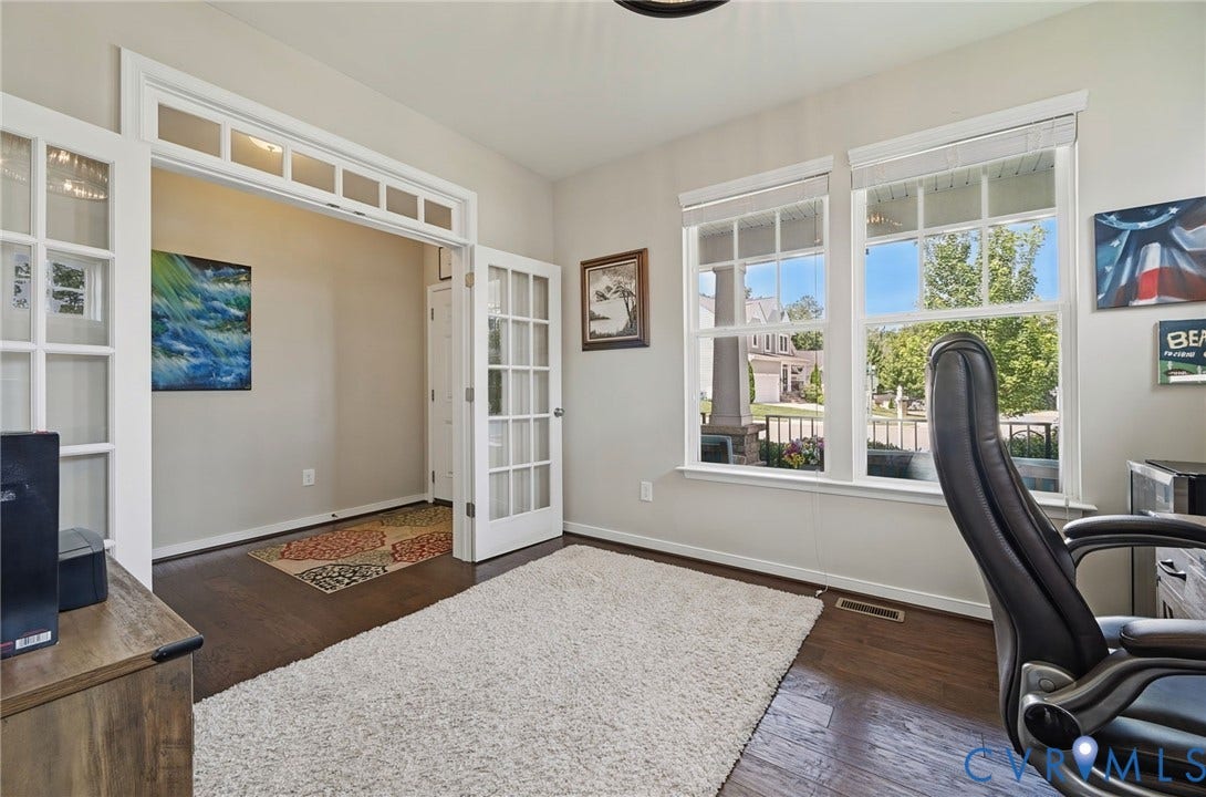 Room featuring wood-finish flooring, multi-pane French doors with transom windows, and multiple windows with white trim