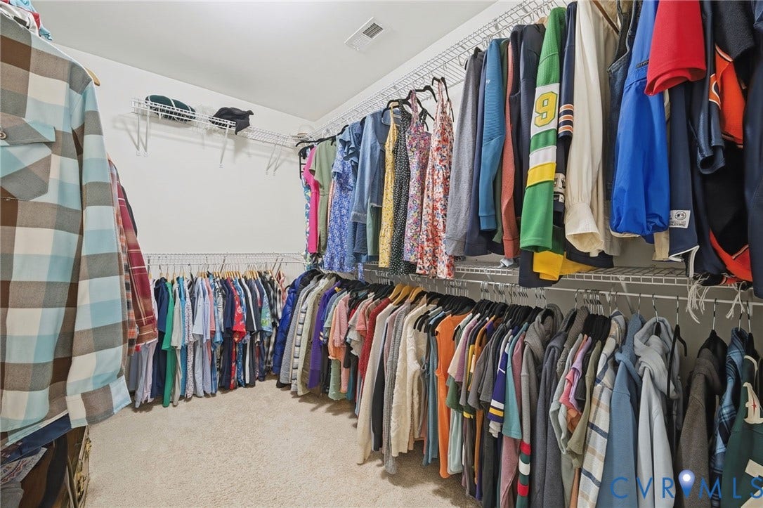 Walk-in closet featuring tiered white wire shelving and wall-to-wall carpeting