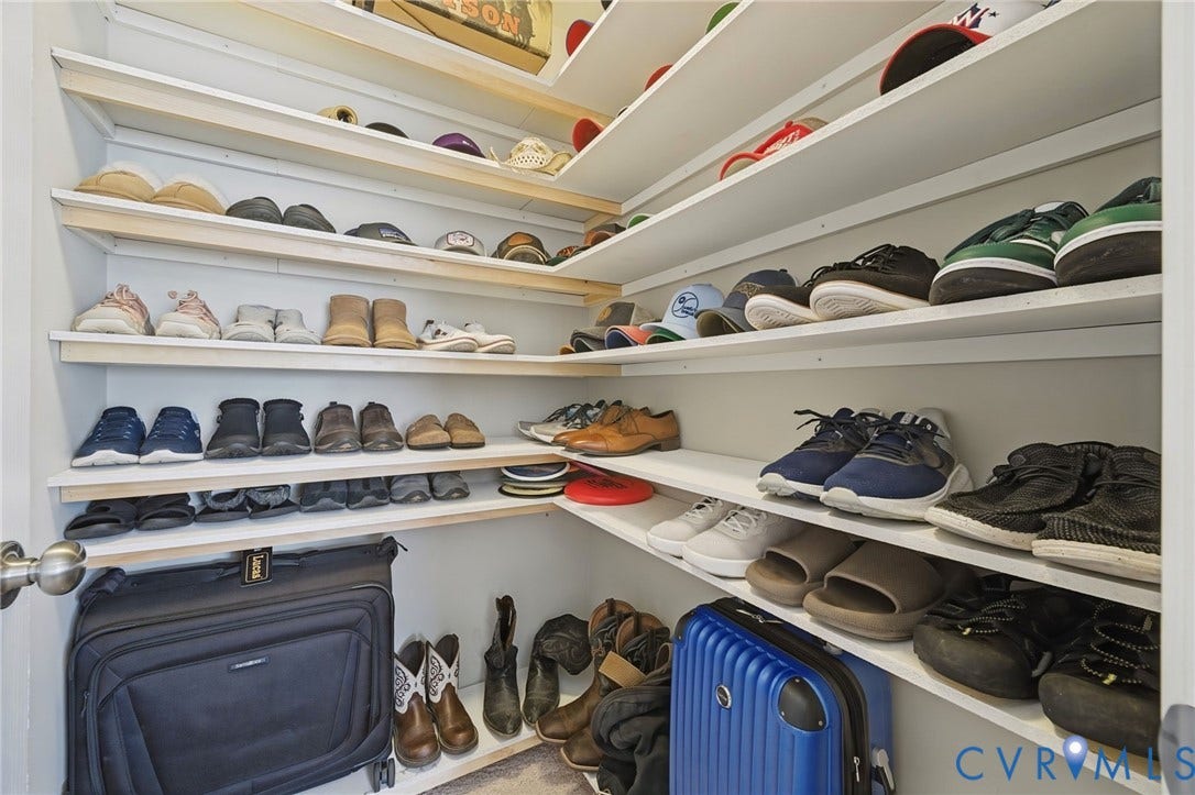 Custom closet featuring tiered, white-painted wooden shelving with corner-cut design and white walls