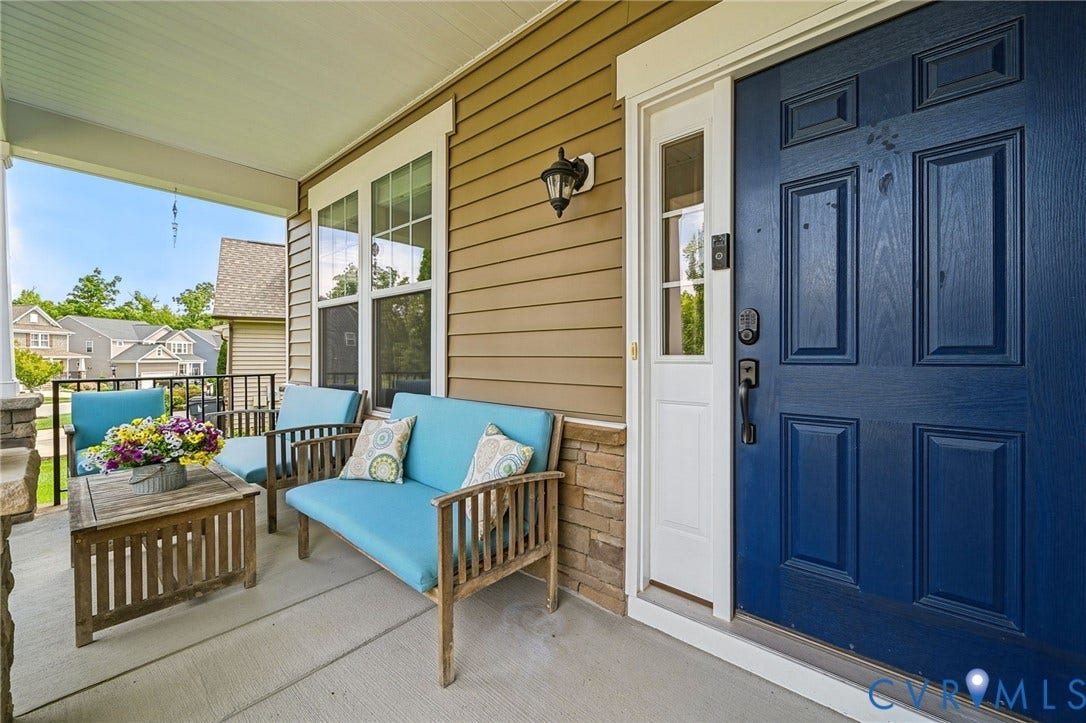 Covered front porch featuring a concrete floor, stone veneer accents, lap siding, a sidelight-equipped door, and an exterior wall-mounted light fixture