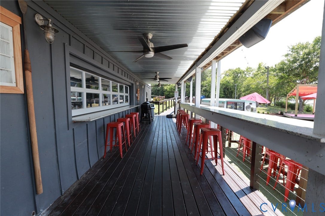 700 Jordan Point Road, North Prince George, VA 23860 Covered outdoor deck featuring a corrugated metal ceiling, dual ceiling fans, built-in bar service counter, and cable railing