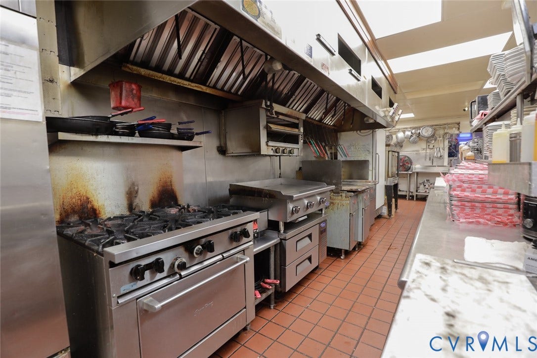 700 Jordan Point Road, North Prince George, VA 23860 Commercial kitchen featuring a stainless steel ventilation hood, industrial-grade range with a built-in oven, flat-top grill, stainless steel prep surfaces, and tile flooring