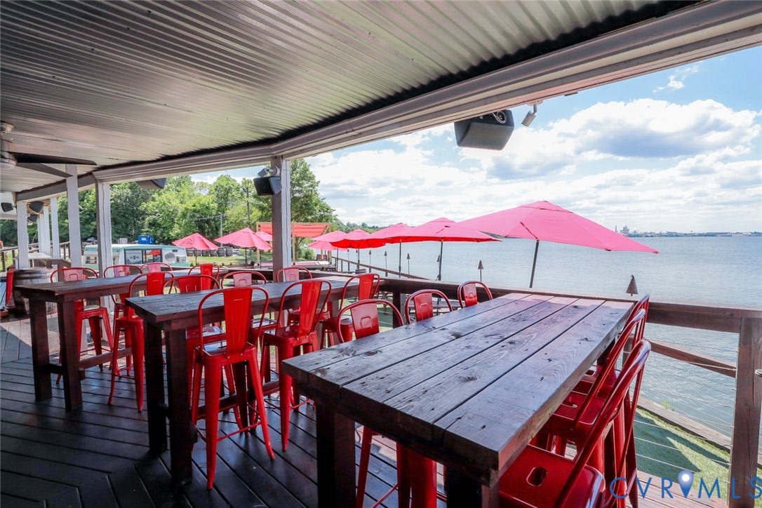 700 Jordan Point Road, North Prince George, VA 23860 Covered deck with corrugated metal ceiling, wood plank flooring, and wooden railings overlooking a body of water