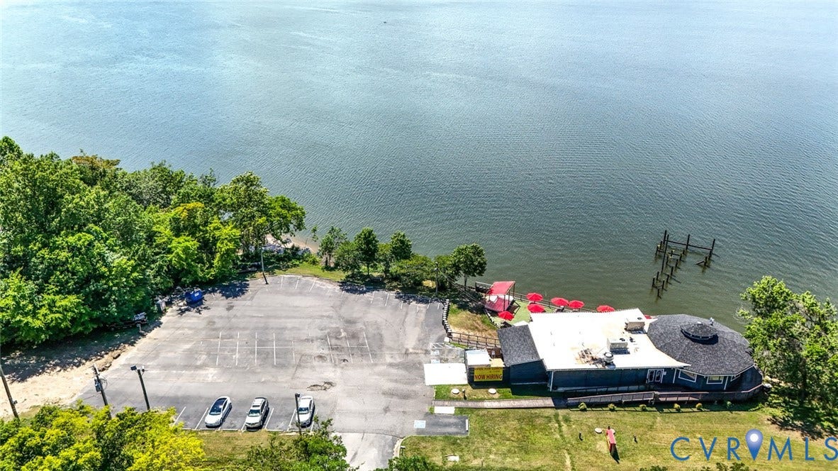 700 Jordan Point Road, North Prince George, VA 23860 Waterfront property featuring an expansive asphalt parking lot, private pier pilings, and mature perimeter trees