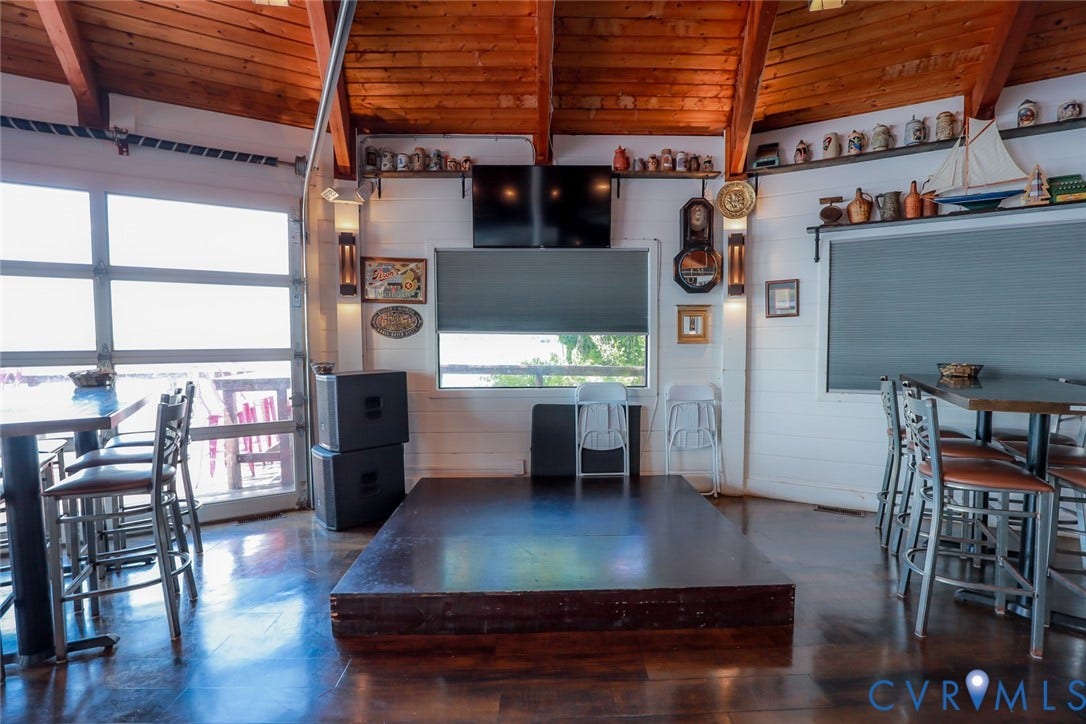 700 Jordan Point Road, North Prince George, VA 23860 Exposed wood-beam vaulted ceiling with tongue-and-groove planking, polished wood-finish flooring, glass-paned roll-up garage door, raised wood platform, and built-in wall-mounted shelving