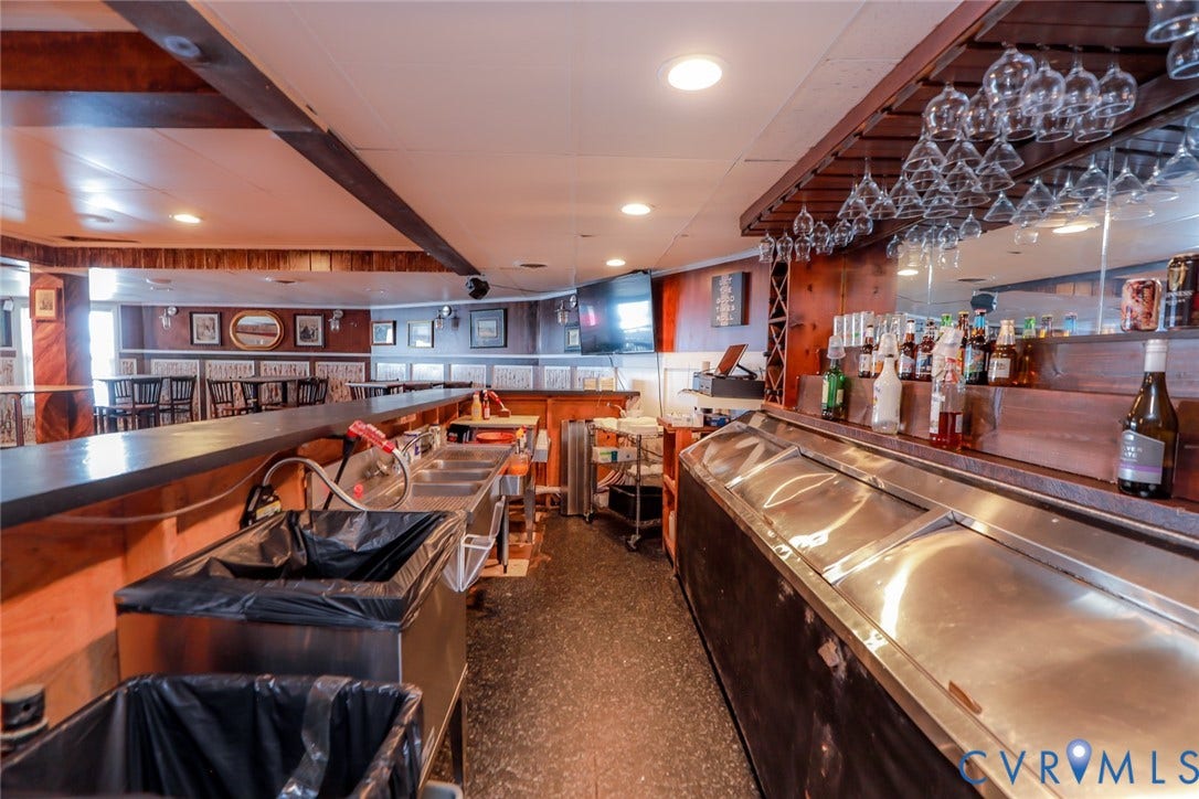 700 Jordan Point Road, North Prince George, VA 23860 Custom wooden bar area featuring a built-in multi-basin stainless steel sink, glass stemware rack, mirrored backsplash, and recessed lighting