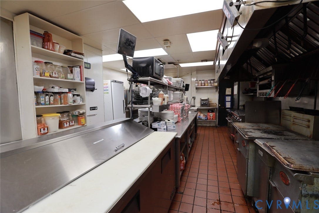 700 Jordan Point Road, North Prince George, VA 23860 Commercial kitchen featuring stainless steel food preparation stations, built-in shelving, high-capacity ventilation hood, professional-grade range, and tile flooring