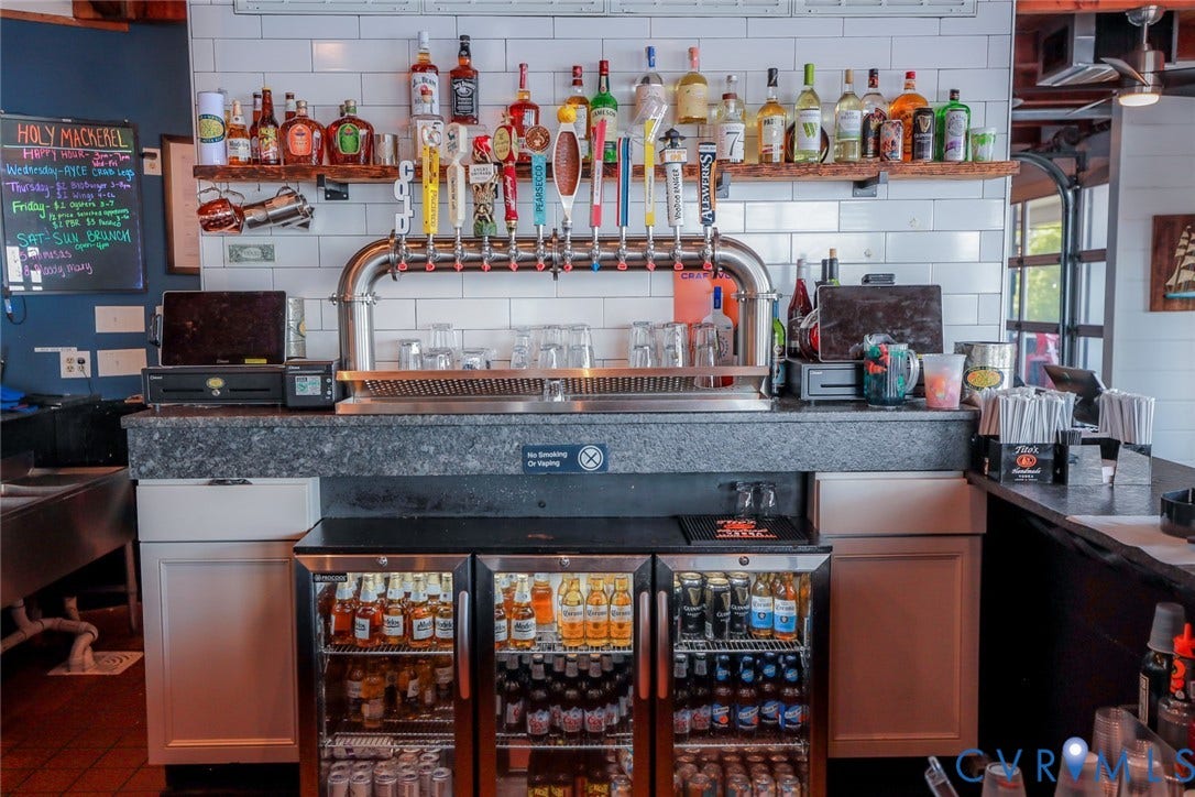 700 Jordan Point Road, North Prince George, VA 23860 Custom bar station featuring a professional multi-tap draft system, white subway tile backsplash, stone-surface countertop, built-in triple-door glass refrigeration, and floating wood shelving