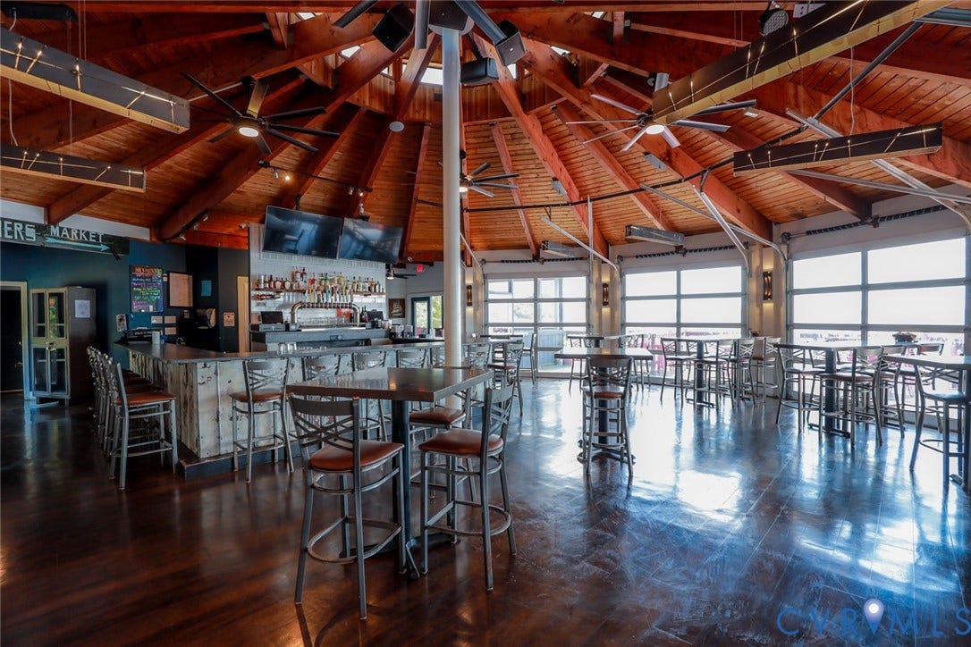 700 Jordan Point Road, North Prince George, VA 23860 Vaulted wood-paneled ceiling with exposed beams, polished wood-finish flooring, full-length roll-up glass garage doors, and integrated bar counter with built-in draft system