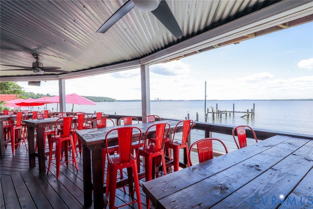 700 Jordan Point Road, North Prince George, VA 23860 Covered waterfront deck featuring corrugated metal roofing, ceiling fans, wood-plank decking, and perimeter railing