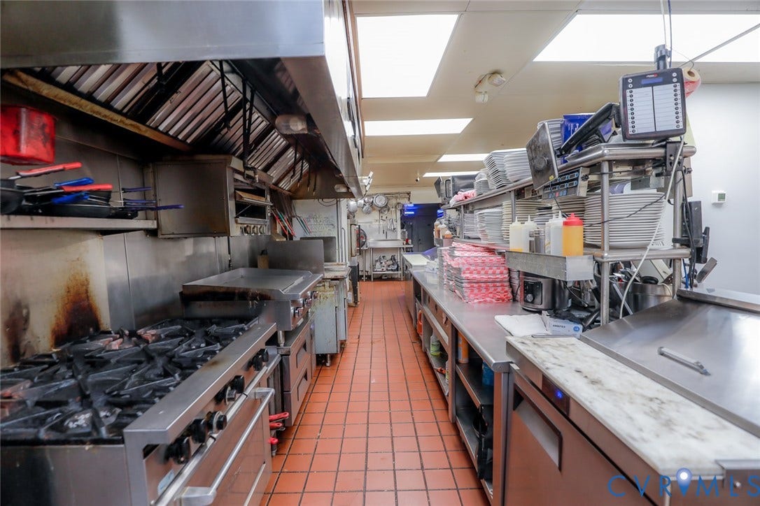 700 Jordan Point Road, North Prince George, VA 23860 Commercial kitchen featuring a stainless steel range, heavy-duty ventilation hood, stainless steel work surfaces, and tiled flooring