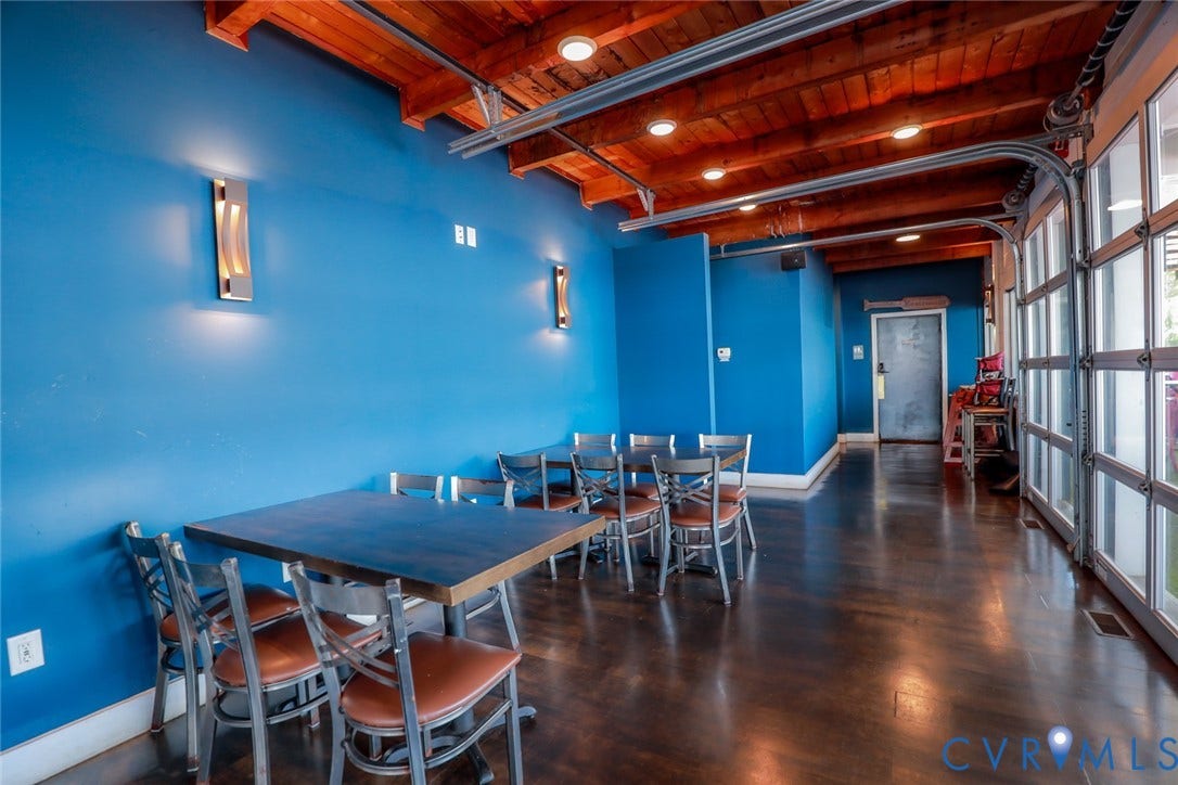 700 Jordan Point Road, North Prince George, VA 23860 Exposed wood-beam ceiling with recessed lighting, stained concrete flooring, full-wall glass garage door, and modern wall-mounted sconces