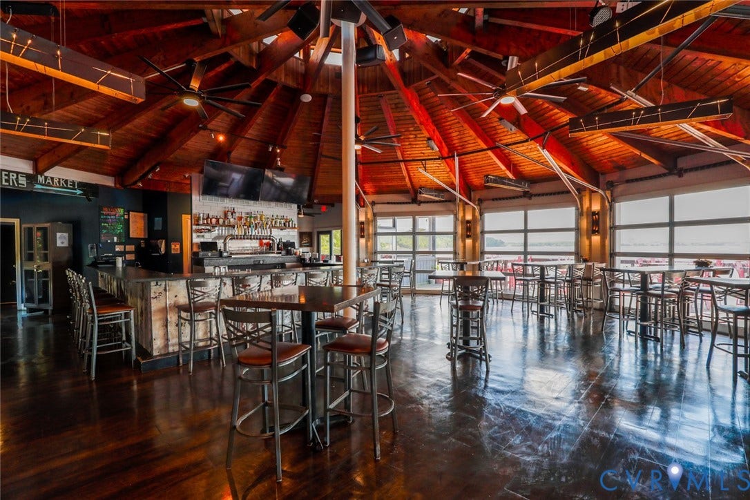 700 Jordan Point Road, North Prince George, VA 23860 Exposed wood beam vaulted ceiling with a circular design, polished wood flooring, built-in bar, and glass-paneled garage-style wall partitions