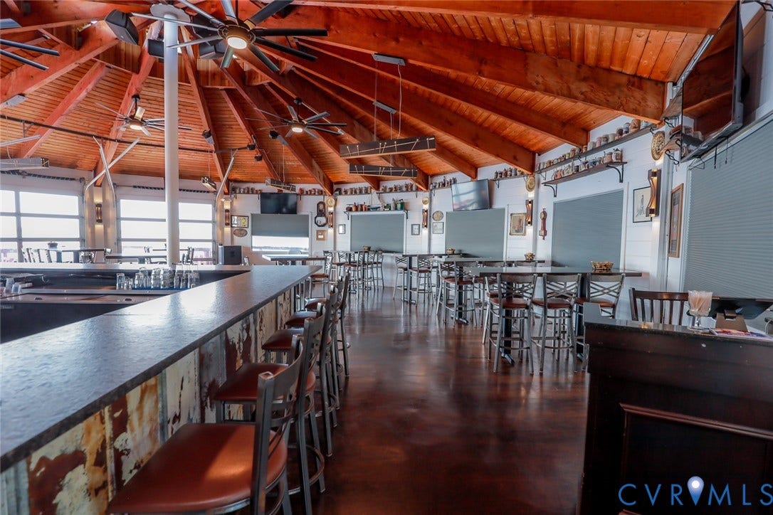 700 Jordan Point Road, North Prince George, VA 23860 Expansive circular room featuring a vaulted, radial wood-beam ceiling, polished concrete flooring, built-in bar with dark stone-surface countertops, and rustic metal-panel detailing