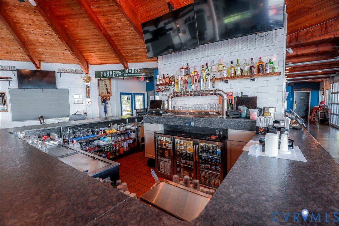700 Jordan Point Road, North Prince George, VA 23860 Full-service bar area featuring a wrap-around stone-finish countertop, multi-tap draft system, under-counter refrigeration, tile backsplash, and vaulted wood-paneled ceiling