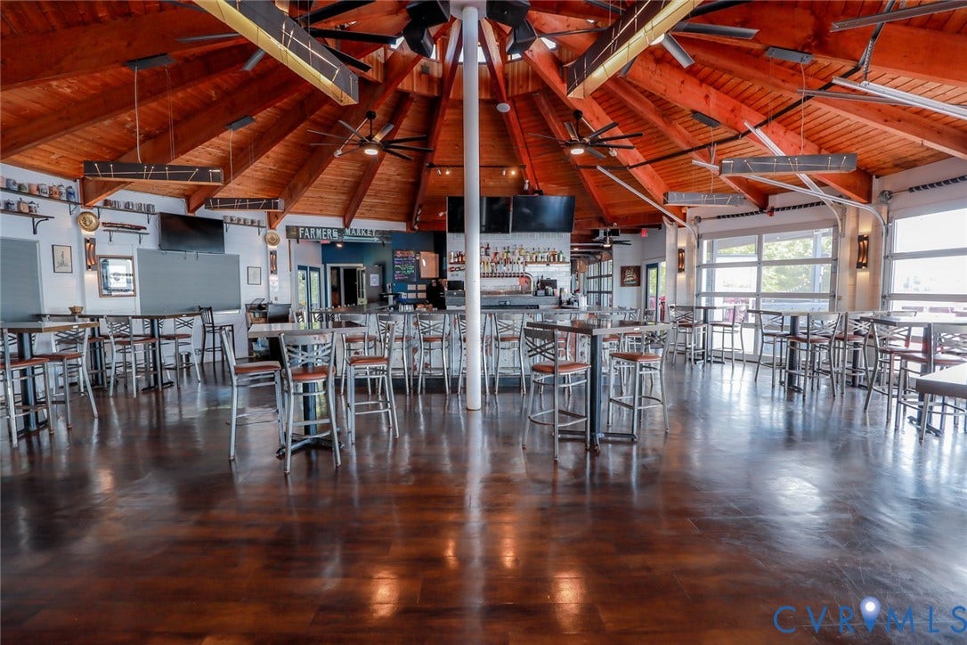 700 Jordan Point Road, North Prince George, VA 23860 Expansive circular interior featuring a vaulted wood-beam ceiling, high-gloss polished concrete flooring, multiple ceiling fans, and overhead glass-paneled garage-style doors