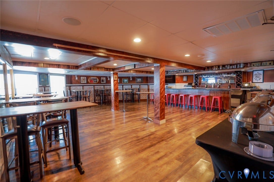 700 Jordan Point Road, North Prince George, VA 23860 Open-concept space featuring wood-finish flooring, a built-in bar with mirror backing, recessed lighting, and wood-paneled structural columns