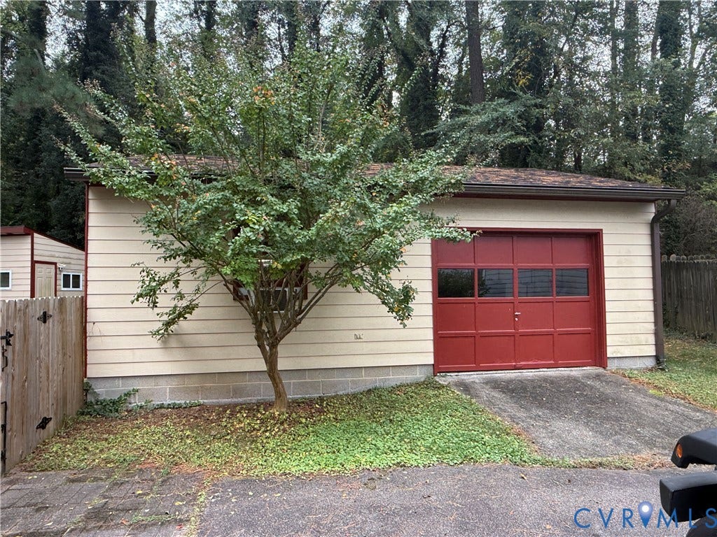 237 Spring Drive, Franklin, VA 23834 Detached garage featuring light-colored horizontal siding, a red sectional garage door with window panels, and a concrete driveway apron