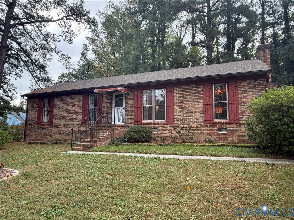 237 Spring Drive, Franklin, VA 23834 Brick exterior featuring red shutters, a gable roof, a brick chimney, and a metal-railed entrance