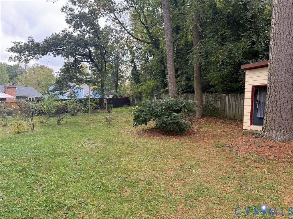 237 Spring Drive, Franklin, VA 23834 Expansive rear grounds featuring mature trees, wood fencing, and a detached storage structure