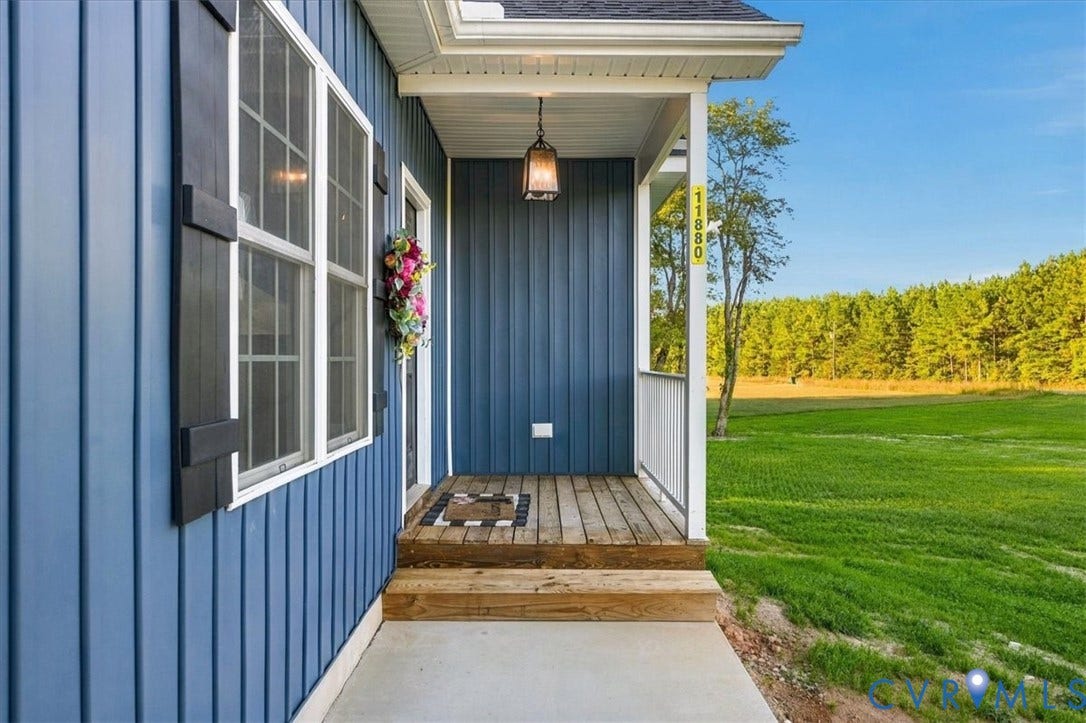 11880 Fosters Lane, Amelia, VA 23002 Covered entryway with vertical blue siding, wood-plank decking, attached hanging light fixture, and contrasting black shutters