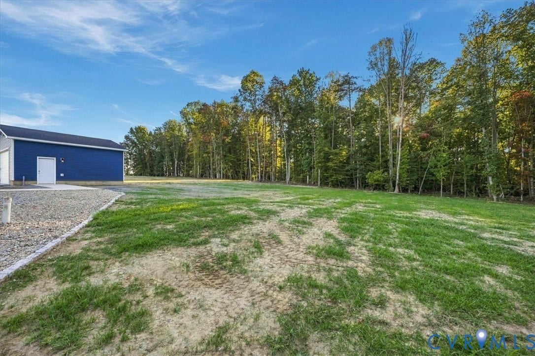 11880 Fosters Lane, Amelia, VA 23002 Single-story residence featuring a gray exterior, a detached garage, and a gravel driveway situated on a cleared lot with mature trees
