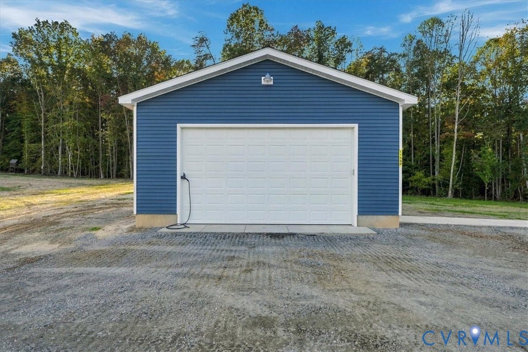 11880 Fosters Lane, Amelia, VA 23002 Detached garage featuring blue vinyl siding, a white overhead door, a concrete foundation, and an exterior wall-mounted light fixture