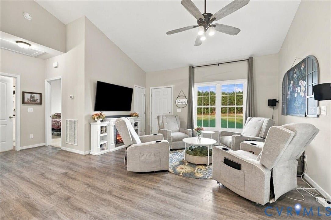 11880 Fosters Lane, Amelia, VA 23002 Living area featuring vaulted ceilings, wood-finish flooring, a built-in media console with an integrated fireplace, and a ceiling fan with multi-light fixture
