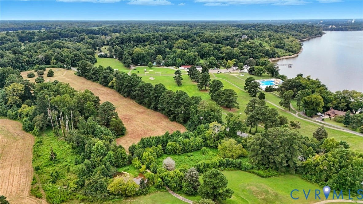 1100 Jordan Point Road, North Prince George, VA 23860 Aerial perspective featuring expansive acreage, mature tree clusters, open grass fields, and immediate proximity to a large body of water