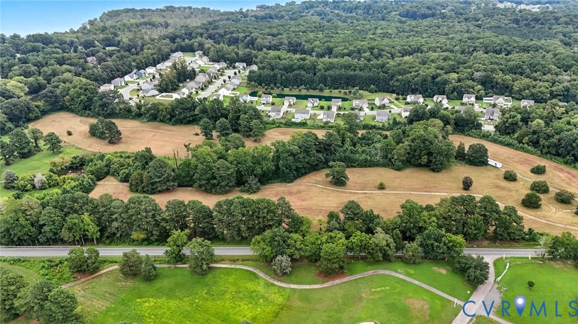 1100 Jordan Point Road, North Prince George, VA 23860 Aerial perspective of expansive acreage featuring vast open grassy fields, densely wooded areas, mature tree lines, and paved pathways