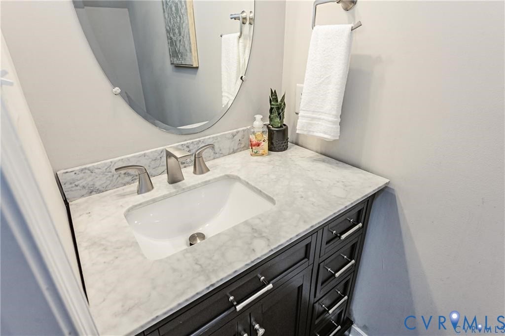 1324 Stone Ridge Park Loop, Henrico, VA 23228 Dark-finish vanity featuring brushed nickel hardware, stone-top counter with an integrated basin, brushed nickel faucet, and oval wall-mounted mirror
