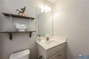 1324 Stone Ridge Park Loop, Henrico, VA 23228 Bathroom featuring a vanity with a white countertop and integrated basin, chrome faucet, wall-mounted mirror, three-light fixture, and two dark-finished wall-mounted shelves