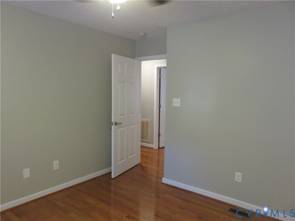 14 N Kalmia Avenue, Henrico, VA 23075 Interior space featuring neutral-toned walls, wood-finish flooring, a white six-panel door, and a ceiling-mounted light fixture