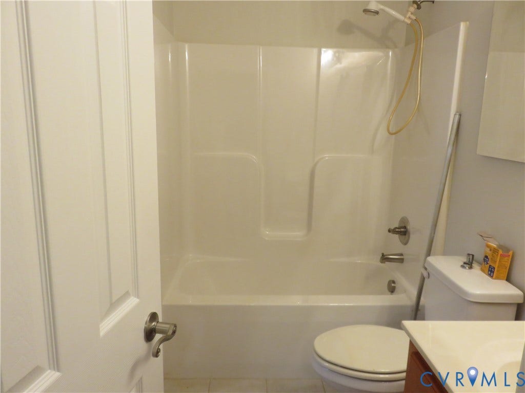 14 N Kalmia Avenue, Henrico, VA 23075 Bathroom featuring a white molded tub-and-shower surround with a handheld showerhead, a dual-handle faucet, a white porcelain toilet, and a vanity with a white countertop