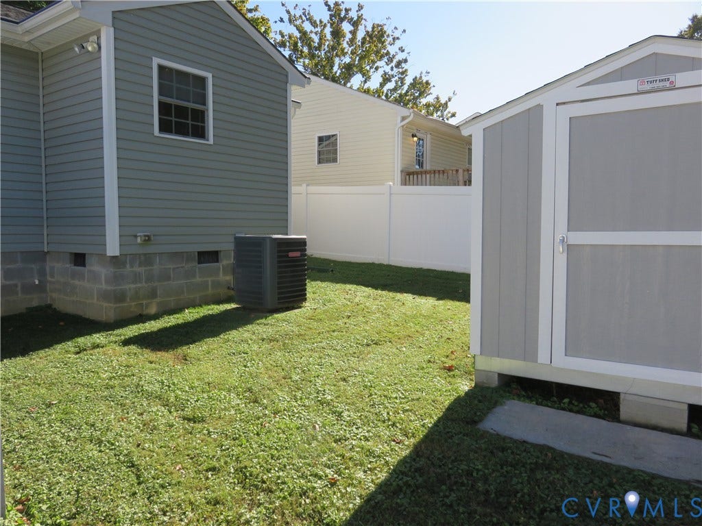 14 N Kalmia Avenue, Henrico, VA 23075 Exterior space featuring a vinyl-sided home with a concrete block foundation, a detached storage building, and a vinyl privacy fence